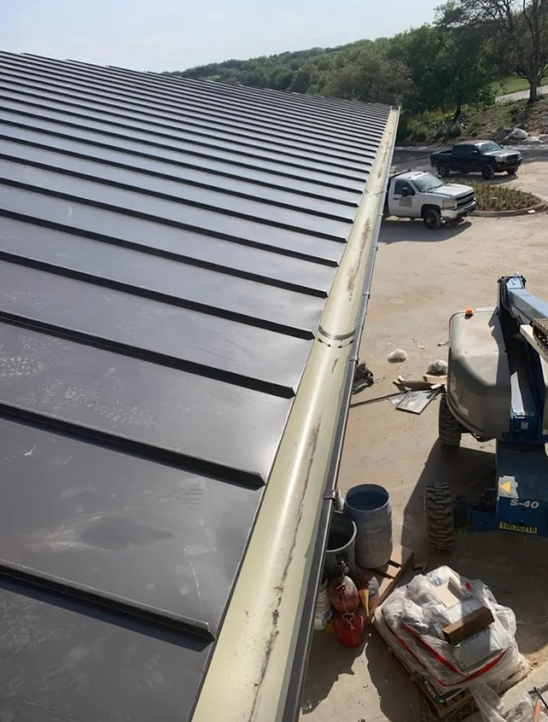 Standing seam panel and gutter detail on a metal roofing jobsite in Mexia